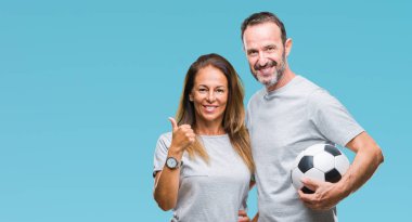 Orta yaş İspanyol çift futbol futbol topu izole arka plan üzerinde mutlu ok işareti yapıyor büyük gülümseme ile tutan parmakları ile mükemmel işareti başparmak