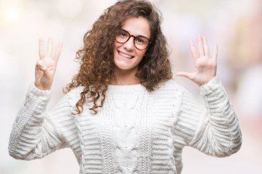Güzel esmer kıvırcık saçlı Genç kız giyiyor kış kazak gösterilen ve parmakları ile işaret izole arka plan üzerinde kendinden emin ve mutlu gülümseyerek süre sekiz numara.