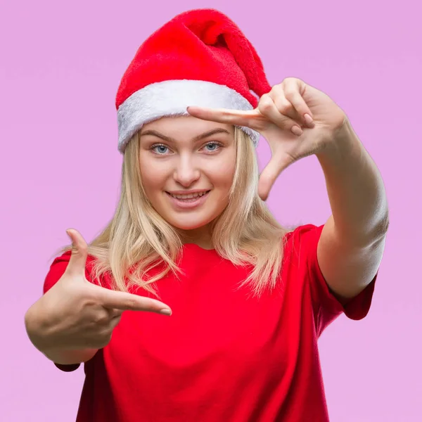 若い白人女性が笑顔の幸せそうな顔で指と手作りフレーム分離の背景にクリスマス帽子をかぶっています 創造性と写真のコンセプト — ストック写真
