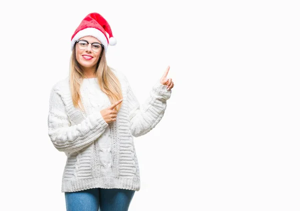 年轻美丽的妇女戴着圣诞节帽子在孤立的背景微笑 看着相机指向用两个手和手指到一边 — 图库照片