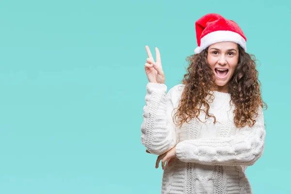 Молодая Брюнетка Рождественской Шляпе Изолированном Фоне Улыбается Счастливым Лицом Подмигивая — стоковое фото