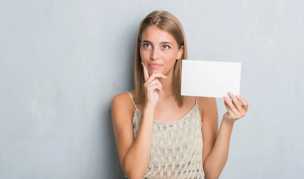 Beautiful Young Woman Grunge Grey Wall Holding Blank Card Serious — Stock Photo, Image