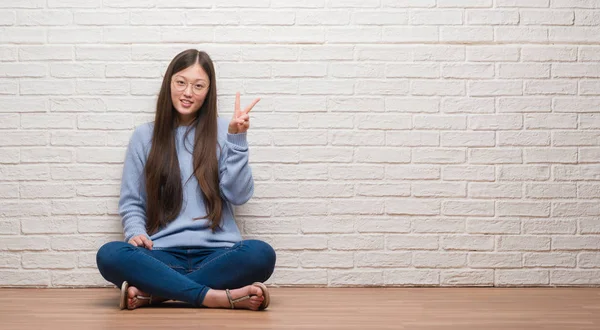 Jovem Chinesa Sentada Chão Sobre Parede Tijolo Mostrando Apontando Para — Fotografia de Stock