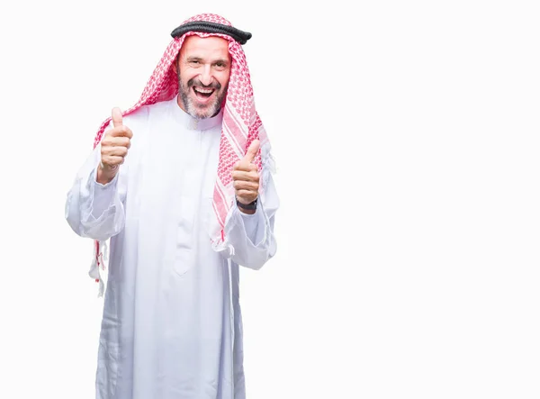 肯定的なジェスチャーを行う分離背景成功記号の上クーフィーヤ身に着けているアラブの年配の男性は親指を笑顔と幸せです 勝者ジェスチャー晴れやかな表情でカメラを見てください — ストック写真