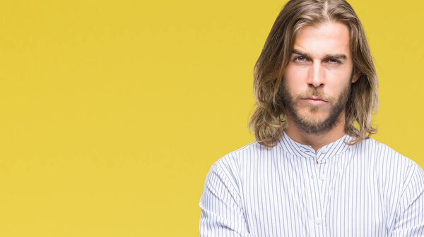 Young handsome man with long hair over isolated background skeptic and nervous, disapproving expression on face with crossed arms. Negative person.