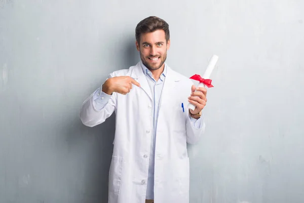 Handsome Young Doctor Man Grey Grunge Wall Holding Diploma Surprise — Stock Photo, Image