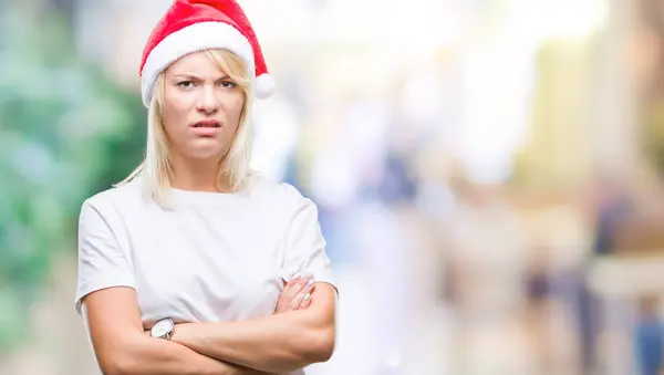 若い美しい金髪女性の懐疑的な孤立した背景と組んだ腕で顔の神経 不賛成式クリスマス帽子をかぶっています 否定的な人 — ストック写真