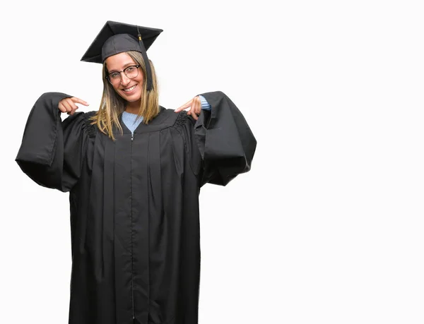 着た若い美しい女性の顔に笑顔と自信を持って 誇りと幸せな指で自分を指している孤立した背景に制服を卒業 — ストック写真