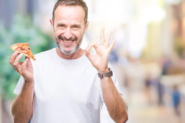 優秀なシンボルの指で サインをして孤立した背景に中年白髪の年配の男性を食べるピザのスライス — ストック写真