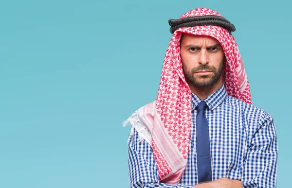 Young handsome arabian business man wearing keffiyeh over isolated background skeptic and nervous, disapproving expression on face with crossed arms. Negative person.