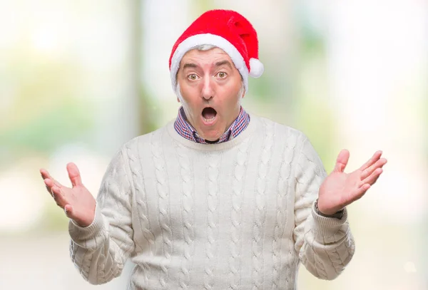 ハンサムな年配の男性にクリスマスの帽子をかぶって狂気を祝う背景を分離した腕を上げると成功のためびっくりし 叫んで興奮して目を開きます 勝者の概念 — ストック写真