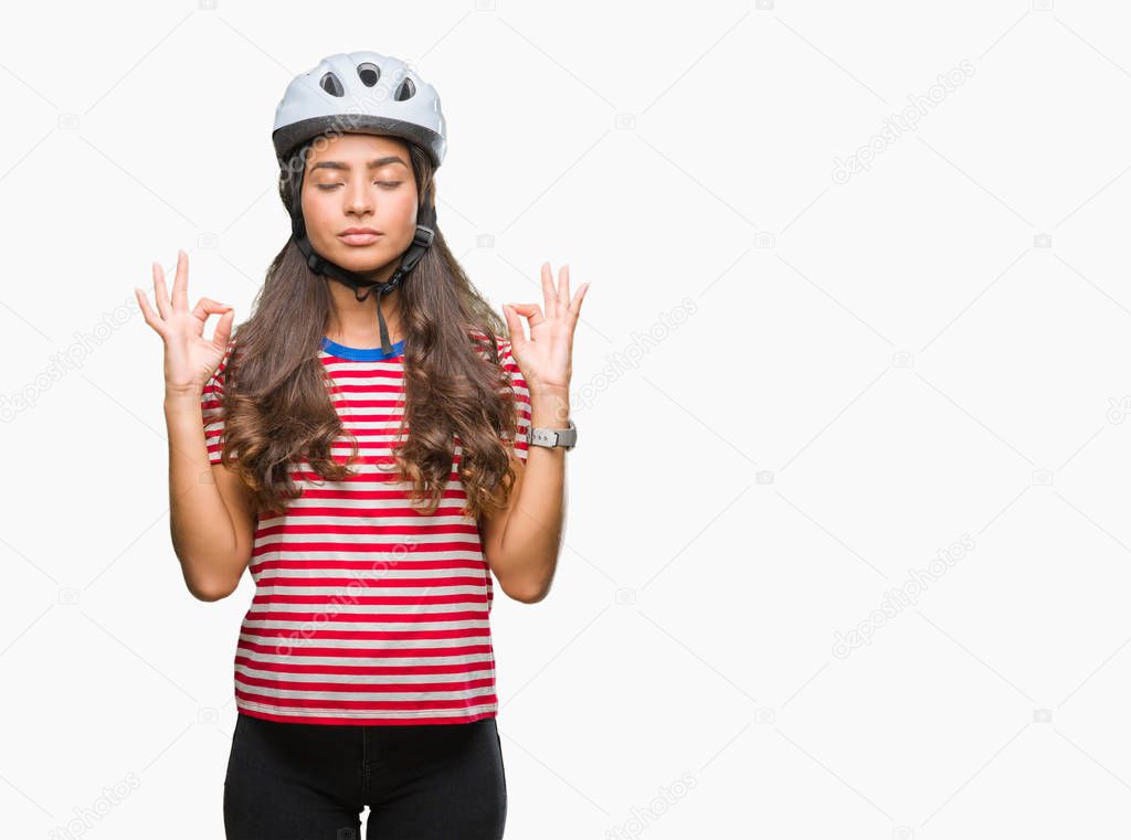 Young arab cyclist woman wearing safety helmet over isolated background relax and smiling with eyes closed doing meditation gesture with fingers. Yoga concept.