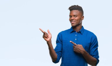 Gülümseyen ve iki elleri ve parmakları ile tarafına işaret kamera bakarak izole arka plan üzerinde genç Afro-Amerikan adam.