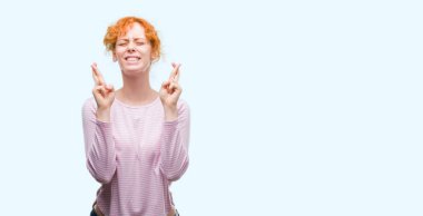 Umut ve gözleri kapalı geçiş parmaklarıyla gülümseyen genç Kızıl saçlı kadın. Şans ve batıl kavramı.