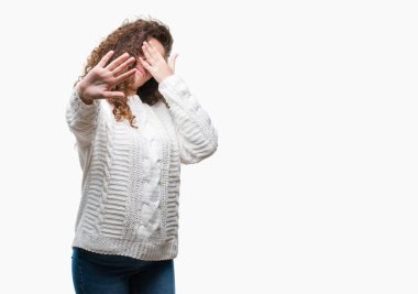 Güzel esmer kıvırcık saçlı Genç kız üzerinde kış kazak giyiyor izole elleriyle gözlerini kapsayan arka plan ve dur jest ile acı ve korku ifadesi. Utandım ve negatif kavramı.