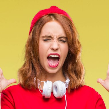 Genç güzel hipster kadın kulaklık ve kızgın ve silah ile başarı için deli kap kutlama izole arka plan üzerinde kaldırdı ve heyecanlı çığlık gözler kapalı. Kazanan kavramı