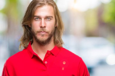 Yüzünde ciddi bir ifade ile izole arka plan üzerinde uzun saçlı Genç yakışıklı adam. Basit ve doğal kameraya bakıyor.