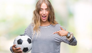 Sürpriz yüz işaret parmağı kendini izole arka plan üzerinde futbol futbol topu tutan genç güzel sarışın kadın