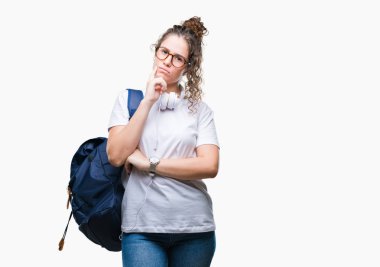 Sırt çantası ve kulaklık üzerinde giyen genç esmer öğrenci kız çene düşünme hakkında soru, dalgın ifade üzerine el ile arka plan izole. Düşünceli yüzüyle gülümsüyor. Şüphe kavramı.