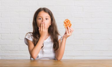 Sessizlik, gizli kavramı gözleme kapak ağız için hata, ifade korku, utanç ile şok el ile yemek masada oturan genç İspanyol çocuk korkuttu