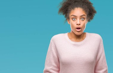 Korkuyor ve şok sürpriz ifade, korku ve heyecan yüz ile izole arka plan üzerinde kış kazak giyen genç afro Amerikan kadın.