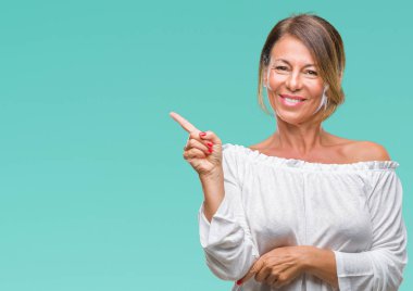 Kameraya bakarak yan el ve parmak ile işaret orta yaş İspanyol kadın kıdemli yüzünde kocaman bir gülümseme ile izole arka plan üzerinde.