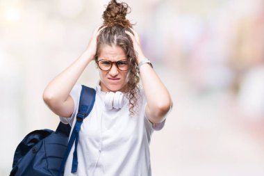 Sırt çantası ve kulaklık çünkü umutsuz ve stresli baş ağrısı acı izole arka plan üzerinde giyen genç esmer öğrenci kız acı ve migren. Ellerini kafasına.