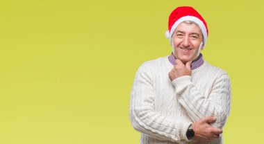 Yakışıklı komuta sizde emin çapraz kollar ve çeneme kaldırdı el ile gülümseme ile kameraya bakarak izole arka plan üzerinde Noel şapka giyiyor. Pozitif düşünce.