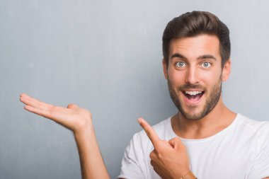 El ve parmak ile işaret çok mutlu gri grunge duvarın üzerinden yakışıklı genç