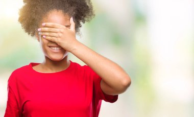 Genç afro Amerikan kadın gülümsüyor ve gözleri için sürpriz kapsayan yüz el ile gülüyor izole arka plan yüzünden. Kör kavramı.