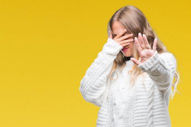 Üzerinde kış kazak giyen güzel genç sarışın kadın izole elleriyle gözlerini kapsayan arka plan ve stop jest ile acı ve korku ifadesi. Utandım ve negatif kavramı.