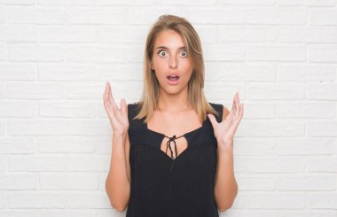 Güzel genç kadın beyaz tuğla duvarın bir sürpriz yüz, korkuyor ve heyecanlı korku ifadesi ile şok korkmuş üzerinden