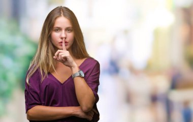 Genç güzel sarışın zarif kadın dudaklarında parmak ile sessiz olmanı izole arka plan üzerinde. Sessizlik ve gizli kavramı.