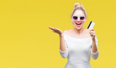 Kredi kartı ile büyük gülümseme çığlık ve ellerini kaldırdı izole arka plan çok mutlu ve heyecanlı, kazanan ifade kutluyor üzerinde zafer tutan genç güzel sarışın kadın