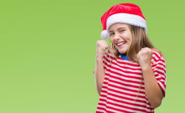 Genç güzel kız izole arka plan kutlama üzerinde Noel şapka şaşırttı ve başarı için kaldırdı kollarını açarak hayrete ve gözleri açık. Kazanan kavramı.