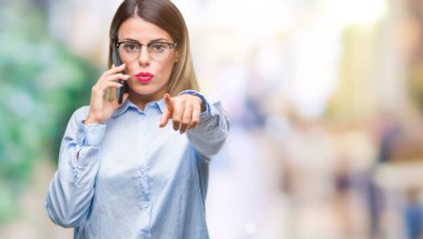 Kamera ve size parmak ile işaret arka plan üzerinde Smartphone kullanarak arama konuşan genç güzel iş kadını izole, el işareti, pozitif ve kendinden emin bir jest ön