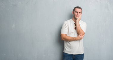 Gri grunge üzerinde beyaz delikanlı duvar düşünme seyir yorgun ve çapraz kolları olan depresyon sorunları ile sıkılmış giyen güneş gözlüğü.