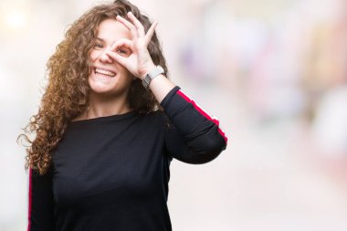 Güzel genç esmer kıvırcık saçlı kız rahat giyiyor bak el gülümseyen, ok jest yapıyor izole arka plan üzerinde göz parmakları ile mutlu yüz üzerinden seyir.