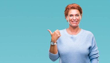 Atrractive üst düzey beyaz Kızıl saçlı kadın arıyorum ve başparmak yanında yukarıyı mutlu yüz ile gülümseyen izole arka plan.