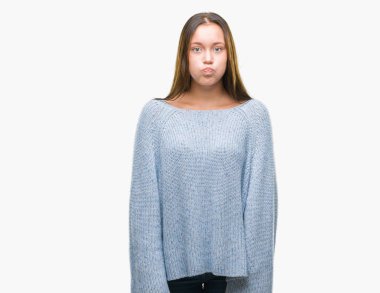 Komik surat ile yanakları şişirme izole arka plan üzerinde kış kazak giyen genç güzel beyaz kadın. Ağız ile hava, deli ifade şişirilmiş.