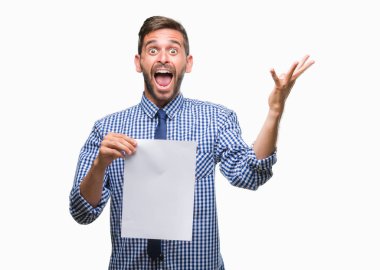 Boş kağıt büyük gülümseme ile çığlık zaferini kutluyor ve ellerini kaldırdı izole arka plan çok mutlu ve heyecanlı, kazanan ifade üzerinde tutan genç yakışıklı adam