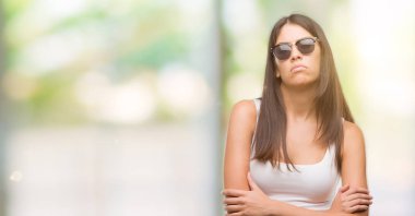 Genç güzel İspanyol güneş gözlüğü şüpheci ve sinir, onaylamayan ifade yüz çapraz kollu giyiyor. Negatif kişi.