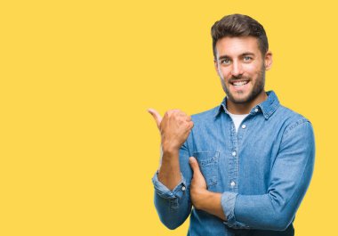 Yakışıklı delikanlı arıyor ve başparmak yanında yukarıyı mutlu yüz ile gülümseyen izole arka plan üzerinde.