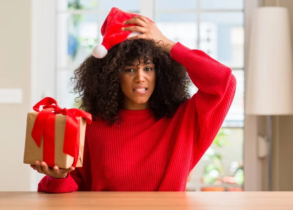 Mulher Afro Americana Segurando Presente Vestindo Chapéu Vermelho Natal Estressado — Fotografia de Stock