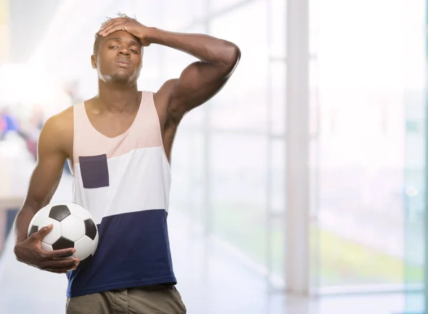 Joven Afroamericano Sosteniendo Pelota Fútbol Estresado Con Mano Cabeza Conmocionado — Foto de Stock