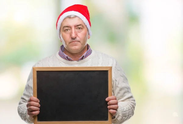 英俊的老人戴着圣诞帽子 并持有黑板在孤立的背景与自信的表情在聪明的脸思考严重 — 图库照片