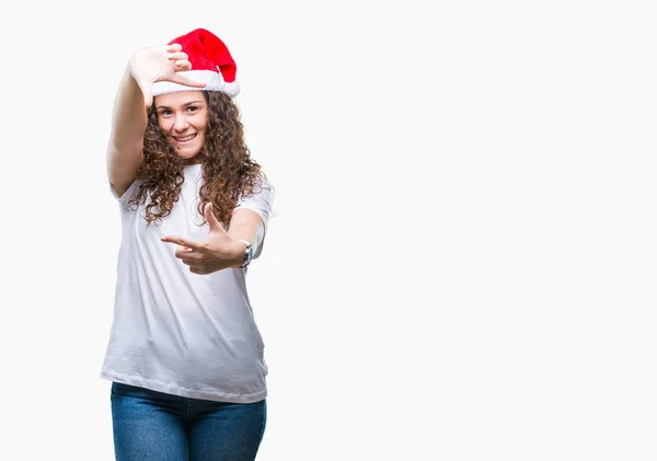 年轻的黑发女孩戴着圣诞帽在孤立的背景微笑框架与手和手指与快乐的脸 创意和摄影理念 — 图库照片