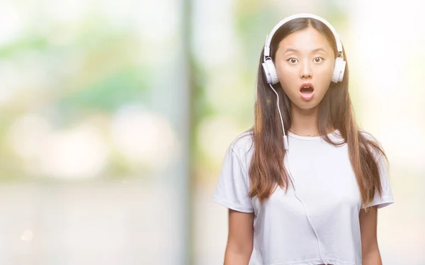 ヘッドフォンを着て音楽を聴く若いアジア女性分離背景驚き顔 恐怖表現と興奮とショックで怖い — ストック写真