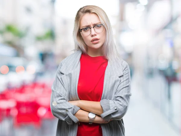 Young blonde business woman wearing fashion jacket over isolated background skeptic and nervous, disapproving expression on face with crossed arms. Negative person.