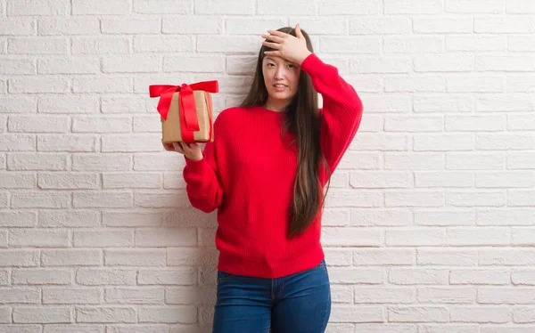 Young Chinese Woman Brick Wall Holding Gift Stressed Hand Head — Stock Photo, Image